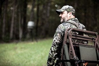 Hunter Walking Across Field to Set Up Treestand 