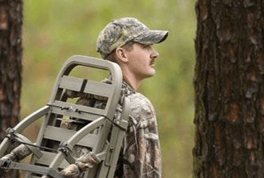 Hunter Carrying Tree Stand Through Woods 