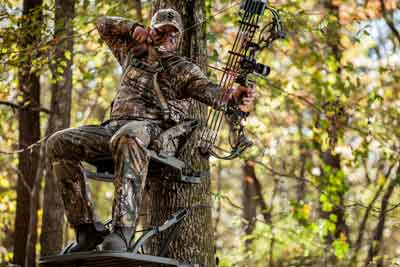 Hunter Sitting in Treestand Drawing Back Bow 