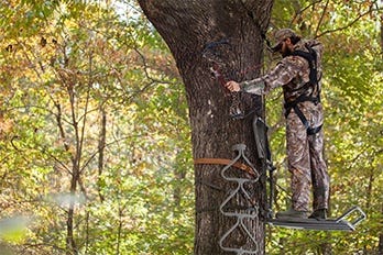 Hunter Drawing Back Bow in Tree Stand 