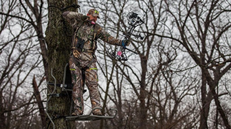 Bowhunter Standing in Treestand Drawing Back Bow 