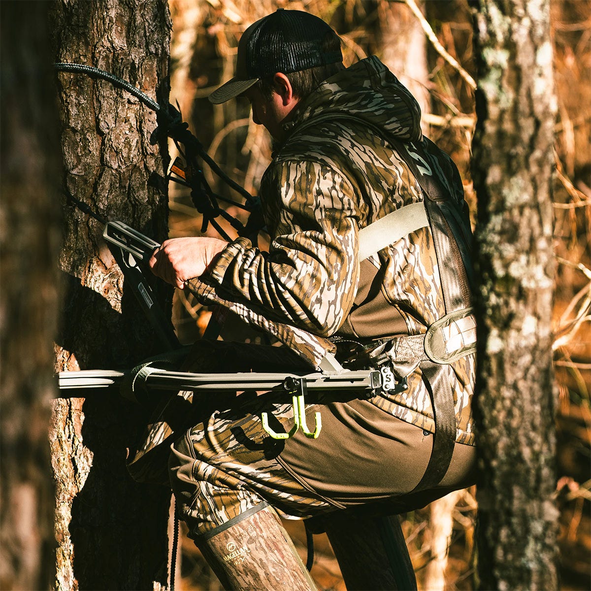 Man in camo is ascending a tree using the Summit Dual Threat PRO SD climbing treestand in Hand Climber mode. The adjustable front bar has been removed.