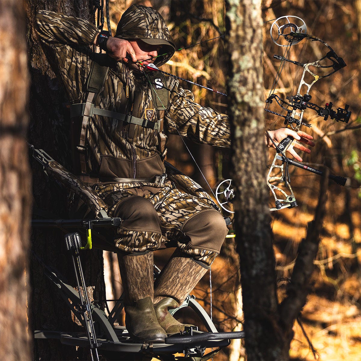 Man in camo draws his bow while seated in the Dual Threat PRO SD that is in the Hand Climber configuration, allowing for a full open front.