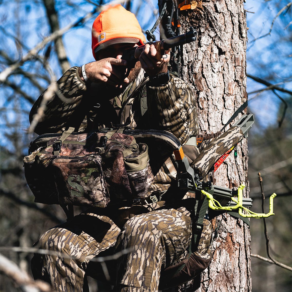 Man sitting in the Summit Dual Threat PRO SD climbing treestand in the Rifle Hunting position. He is using the front bar as a gun rest and pointing his rifle toward a target.