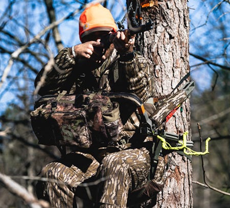 Rifle hunter in the Dual Threat PRO SD treestand with the Deluxe Front Storage Bag and FasTrack Rifle Holder accessories attached